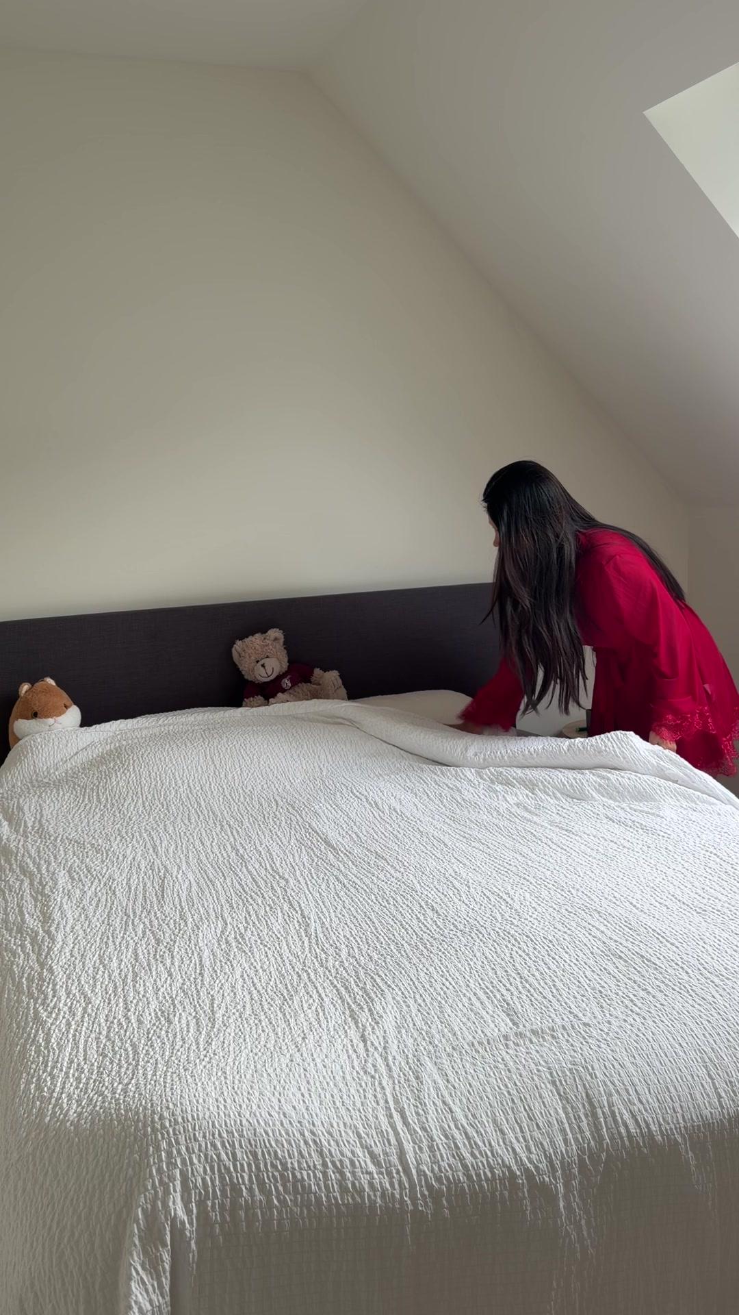 Woman Making Bed in Bedroom
